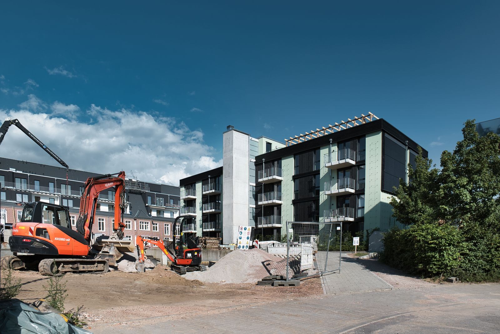 Active construction site with machinery next to modern apartments under blue sky.